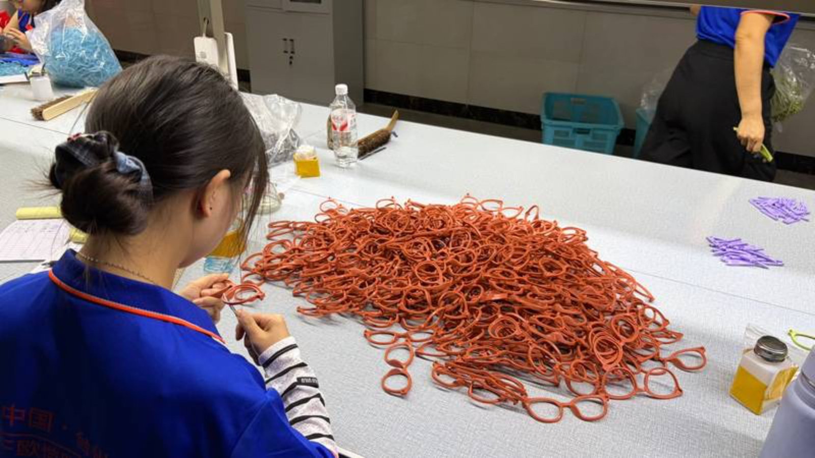 Worker trimming, deburring, and grinding molded frame edges by hand