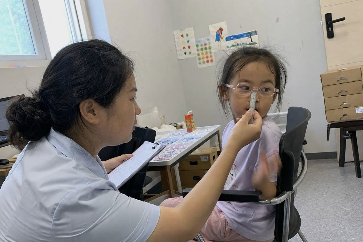 Optician measuring lens width, height, and DBL using the Boxing System on a child (ID#2)